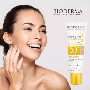 Tube of Bioderma Photoderm Aquafluid SPF 50+ Light Tinted placed beside a smiling face, highlighting dry touch finish and everyday UV defense