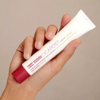 Hand holding ISDIN Cicapost post-scar cream, clinically tested dermatological care for healed scars