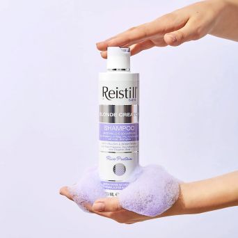 Person dispensing Reistill Blonde Creator purple shampoo into hands with lilac foam, brightening anti-yellow shampoo for blonde and grey hair, 250 ml