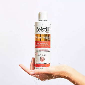 Hand holding Reistill Treatment Daily Shampoo for normal and dry hair showing nourishing formula with sweet almond and honey